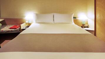 Una habitación de hotel con una cama grande, dos lámparas de noche, una mesita de noche y una silla con cojín rojo.