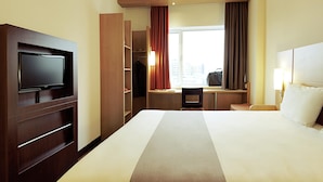 A hotel room with a bed, television, desk, and wardrobe. - ibis London Luton Airport (Luton)