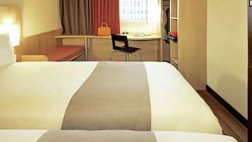 Habitación de hotel con dos camas, un escritorio, una silla, una ventana con cortinas y un armario.