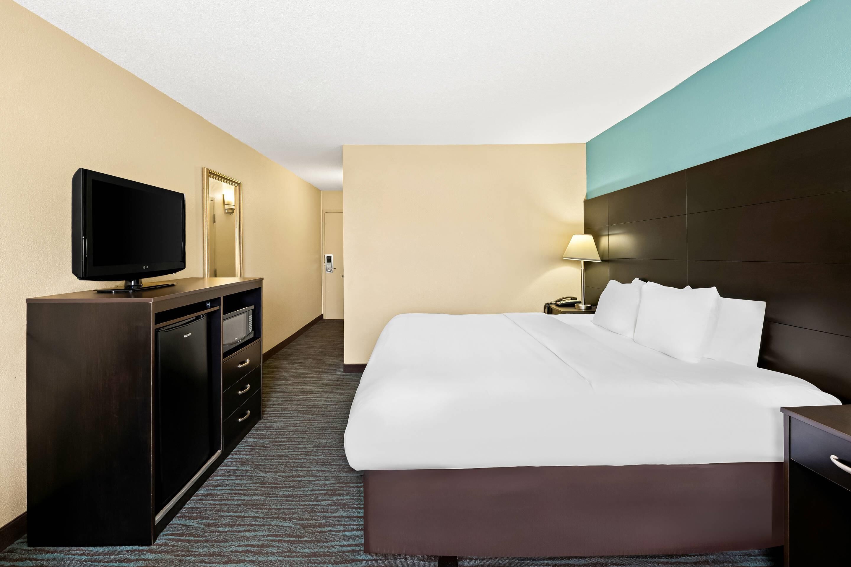 A hotel room with a bed, a TV, a desk, and a lamp.