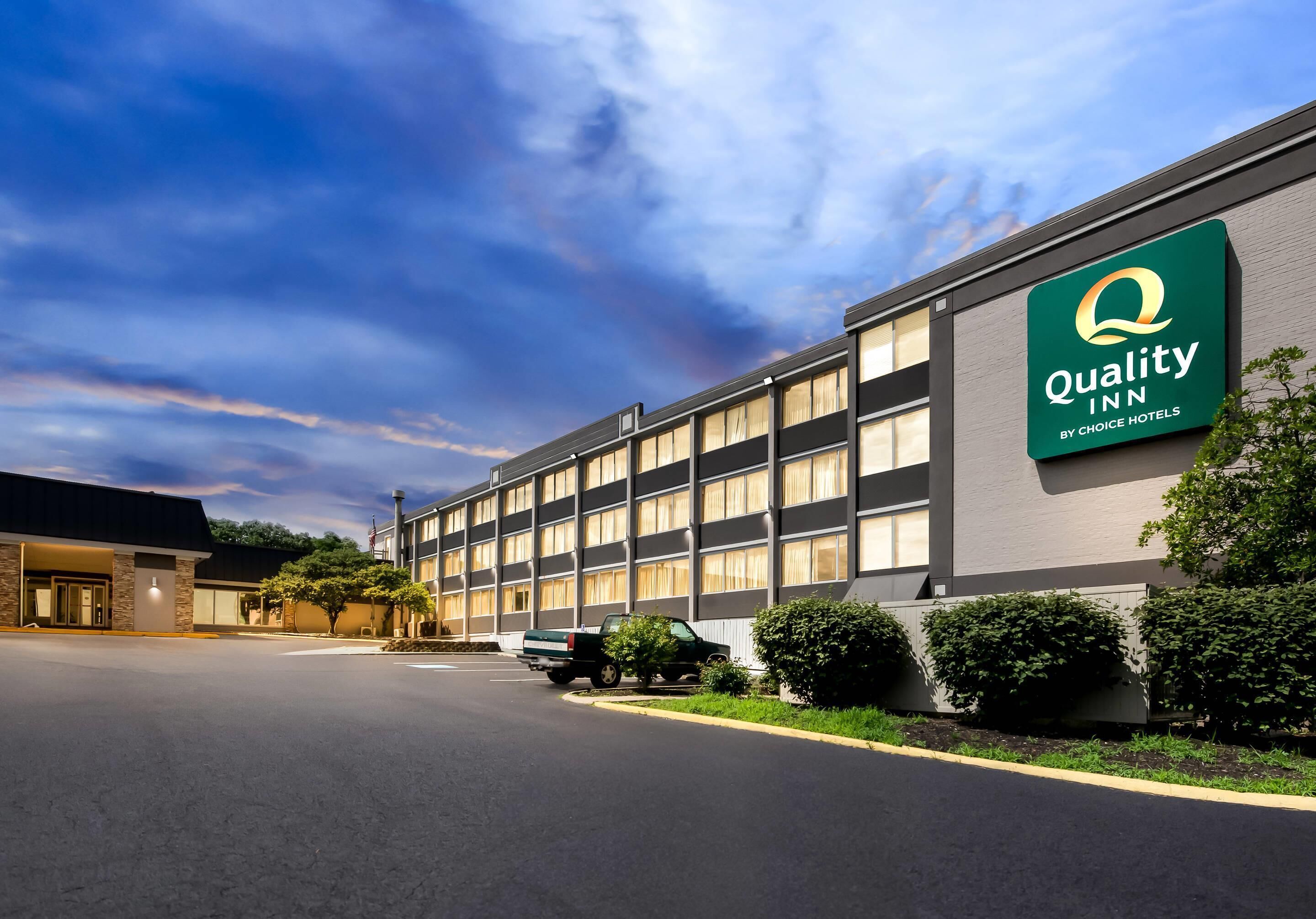 A Quality Inn by Choice Hotels building with a large sign, a parking lot, and a truck parked in front.