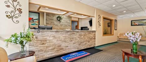 A reception area with a wooden reception desk, a wall-mounted TV, and a reception desk mat.