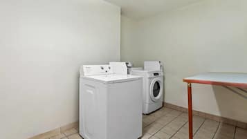 Een wasserette met een wasmachine, droger en een klein tafeltje.