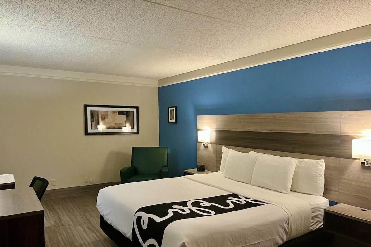Een hotelkamer met een bed, bureau, stoel en nachtkastje.