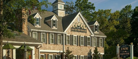 A large, two-story building with a stone facade, a prominent sign reading "Inn on the Square," and a patio area with outdoor seating.