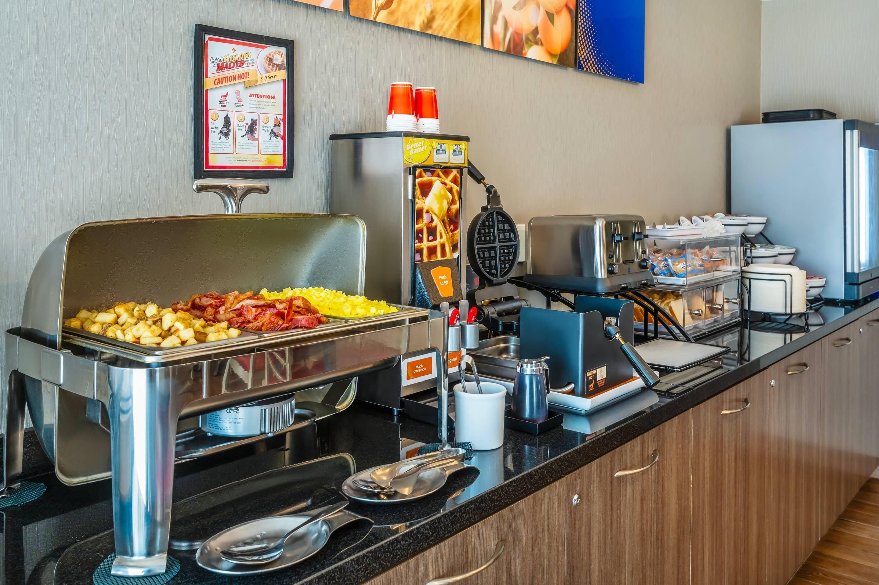 Montaje de bufé con distintos alimentos, una máquina para gofres y una estación de café.