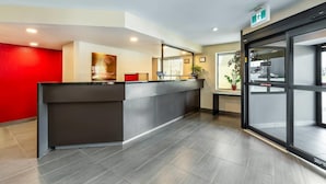 A reception area with a modern counter, a red accent wall, and a large window with a view of the street.