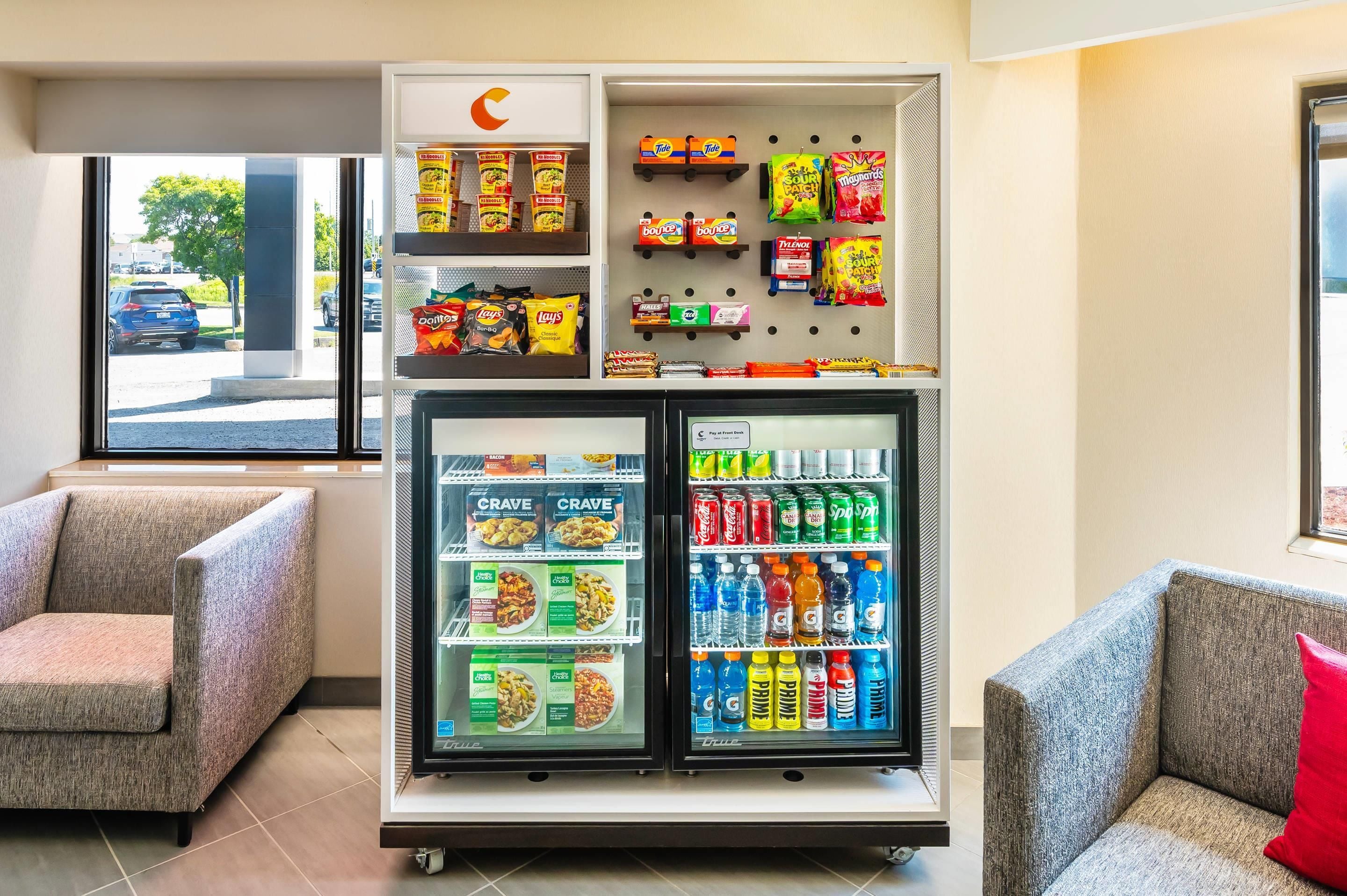 A vending machine with snacks and drinks, located in a room with seating.