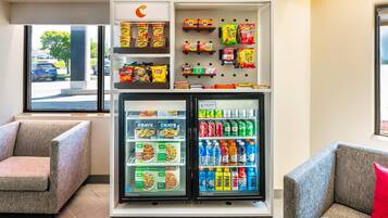 A vending machine with snacks and drinks, located in a room with seating.