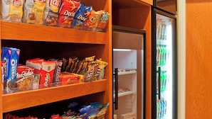 Una cocina con armarios de madera, estantes llenos de aperitivos y un refrigerador.
