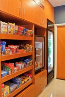 Una cocina con armarios de madera, estantes llenos de aperitivos y un refrigerador.