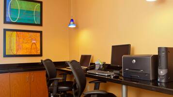 A hotel office with two desks, chairs, computers, and printers.