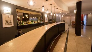 A modern bar area with a curved counter, pendant lighting, and a variety of liquor bottles. - Gran Hotel Buenos Aires (Buenos Aires)