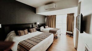 A hotel room with two beds, a TV, a chair, and a window with curtains. - Gran Hotel Buenos Aires (Buenos Aires)