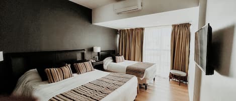 A hotel room with two beds, a TV, a chair, and a window with curtains.