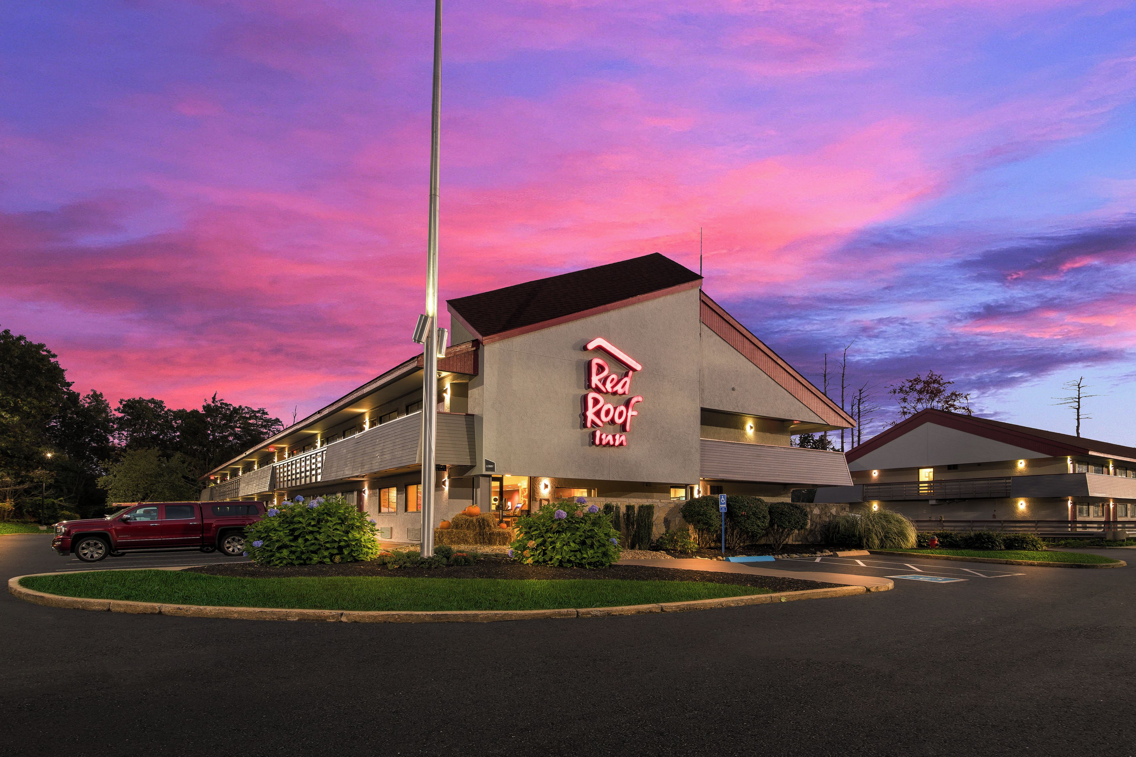 A motel with a prominent neon sign, a parking lot, and a clear sky.