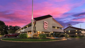 A motel with a prominent neon sign, a parking lot, and a clear sky.