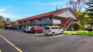 Un motel doté d’un parking, d’un bâtiment aux couleurs rouge et blanche, et d’un escalier menant à l’entrée.