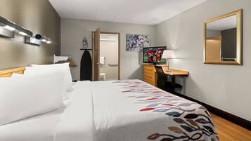 Ein Hotelzimmer mit Bett, Schreibtisch, Fernseher und Spiegel.