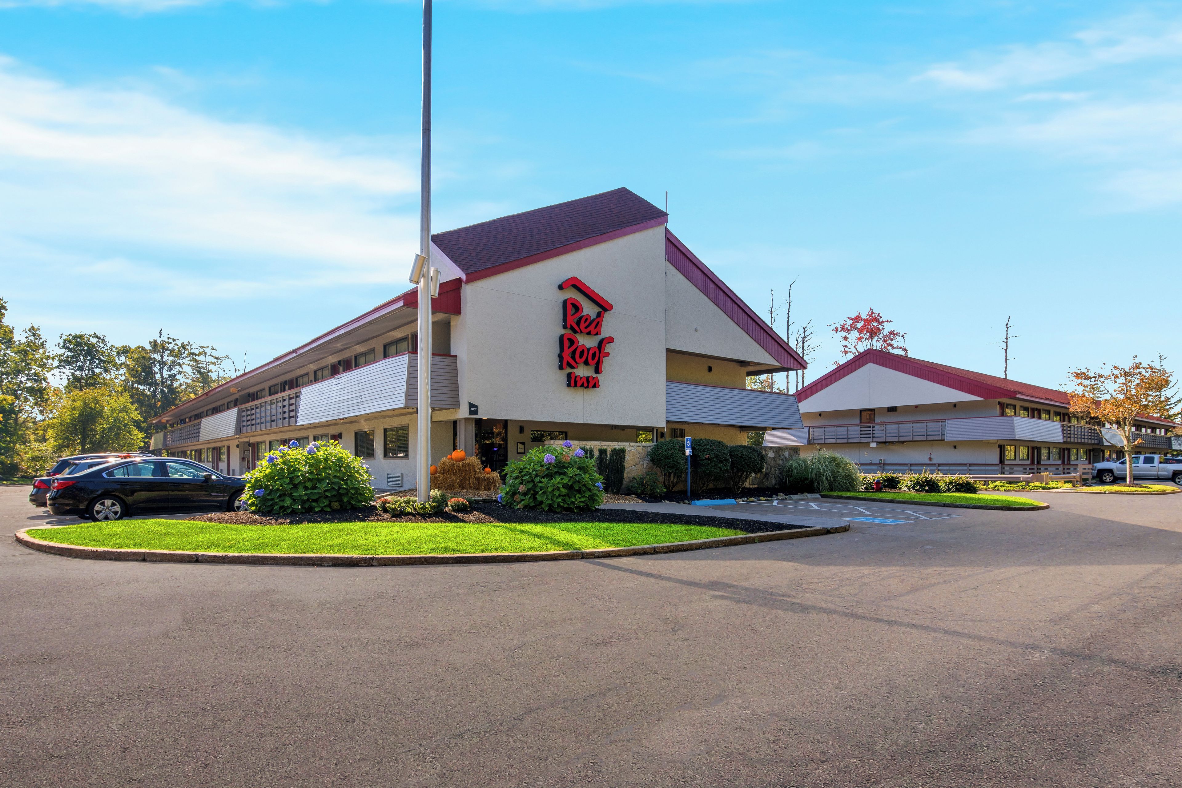 A Red Roof Inn with a parking lot and a landscaped area with plants.