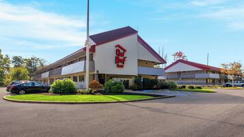 A Red Roof Inn with a parking lot and a landscaped area with plants.