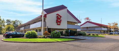 A Red Roof Inn with a parking lot and a landscaped area with plants.