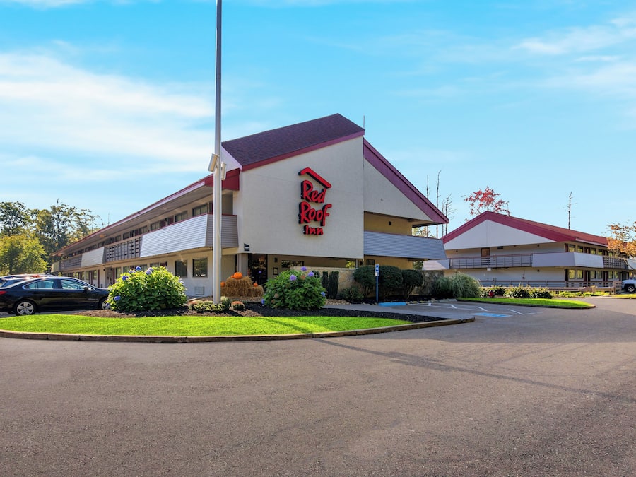 A Red Roof Inn with a parking lot and a landscaped area with plants.