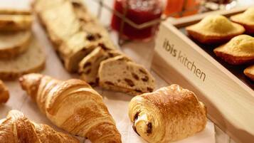 Diverse gebakken producten, zoals croissants en brood, met een label waarop 'Ibis Kitchen' staat.