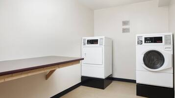 A laundry area with two washing machines, a wooden counter, and a sign indicating cycle times.