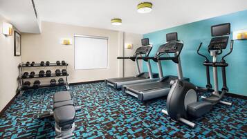 A gym with treadmills, an elliptical, and dumbbells.