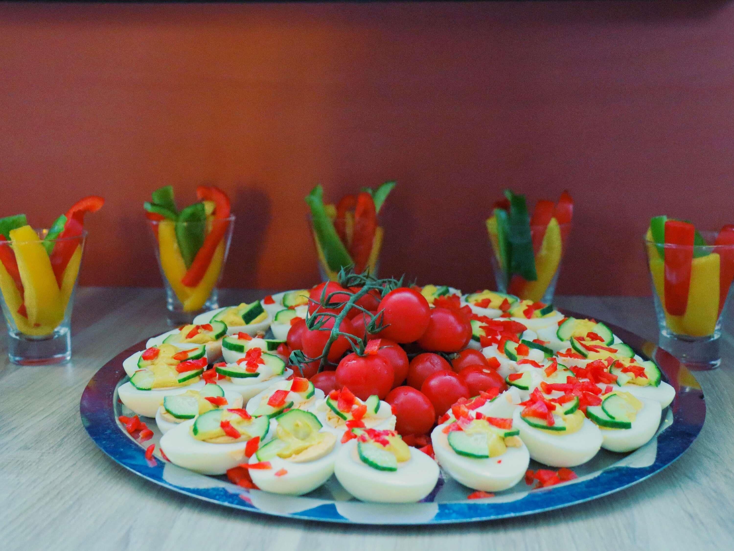 A plate of deviled eggs and cherry tomatoes on a table.