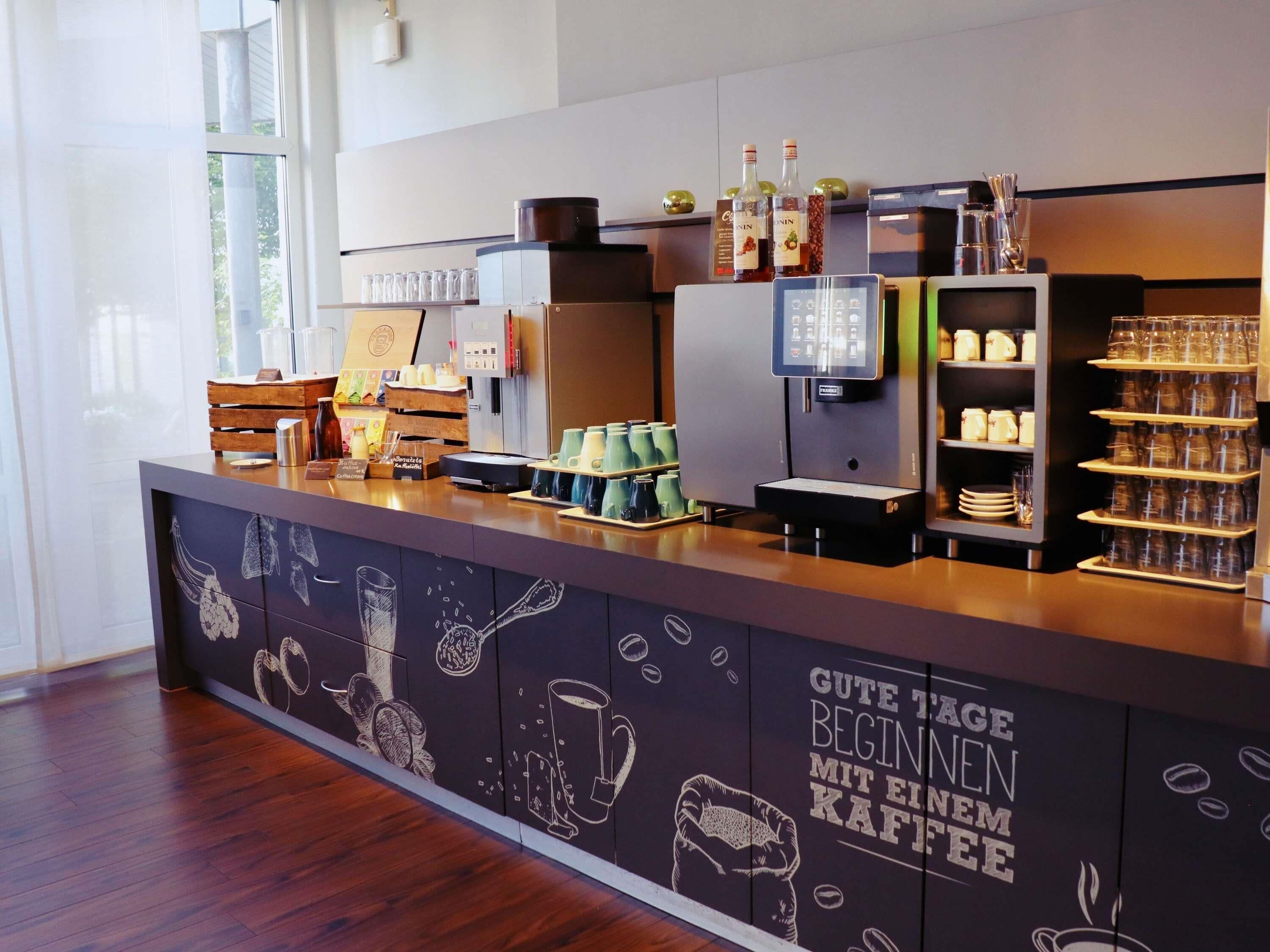 Un comptoir de café avec une machine à café, des tasses et un menu.