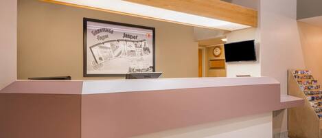 A reception desk with a framed welcome sign, a clock, and a television on the wall.