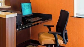 Um espaço de trabalho com computador, uma cadeira e um tapete colorido.