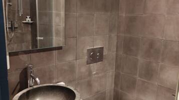Un baño moderno con lavamanos de piedra, inodoro y ducha con cerramiento de vidrio.
