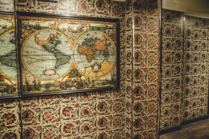 A large, ornate map on a wall with intricate floral wallpaper.
