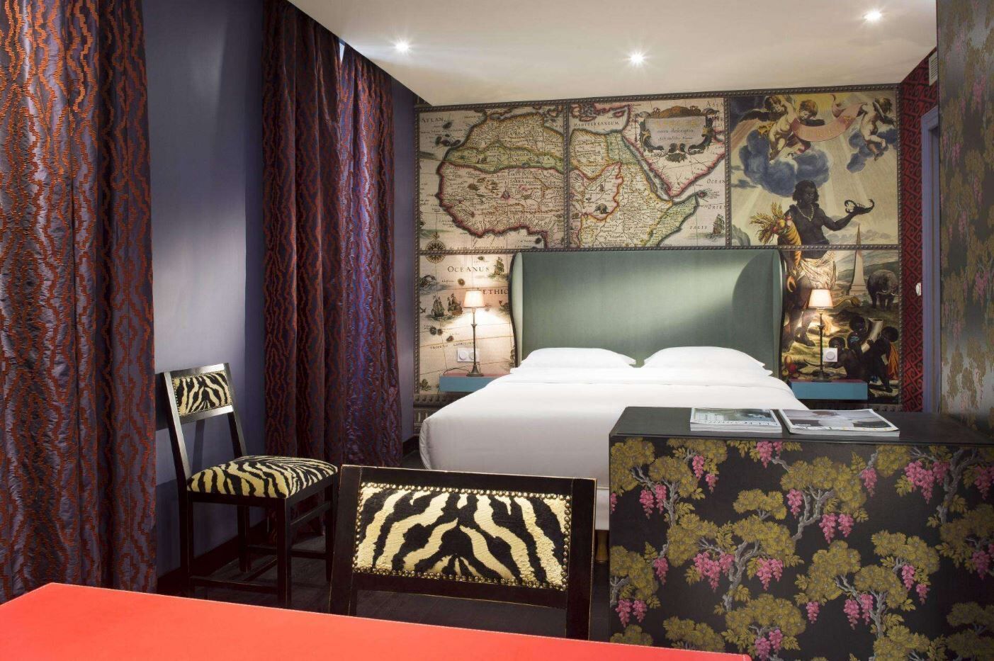 Une chambre d’hôtel avec un lit, une chaise, un bureau, une carte accrochée au mur et des rideaux.