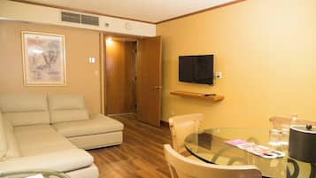 A living room with a sofa, a glass table, and a TV mounted on the wall.