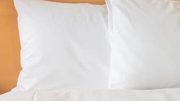 Ein Bett mit weißer Bettwäsche und einem hölzernen Kopfteil.