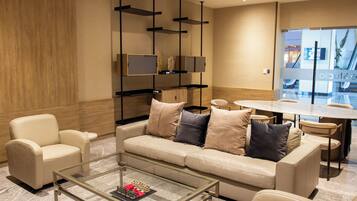 Una sala moderna con sofá, sillones, una mesa de centro y un televisor montado en la pared.