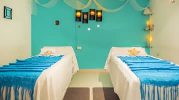 Two beds with white linens and blue bedspreads, each featuring a starfish decoration, are set against a vibrant wall.