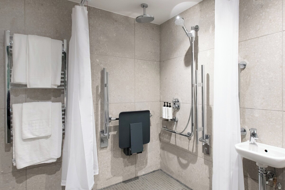 A modern bathroom with a shower, a sink, and a towel rack.