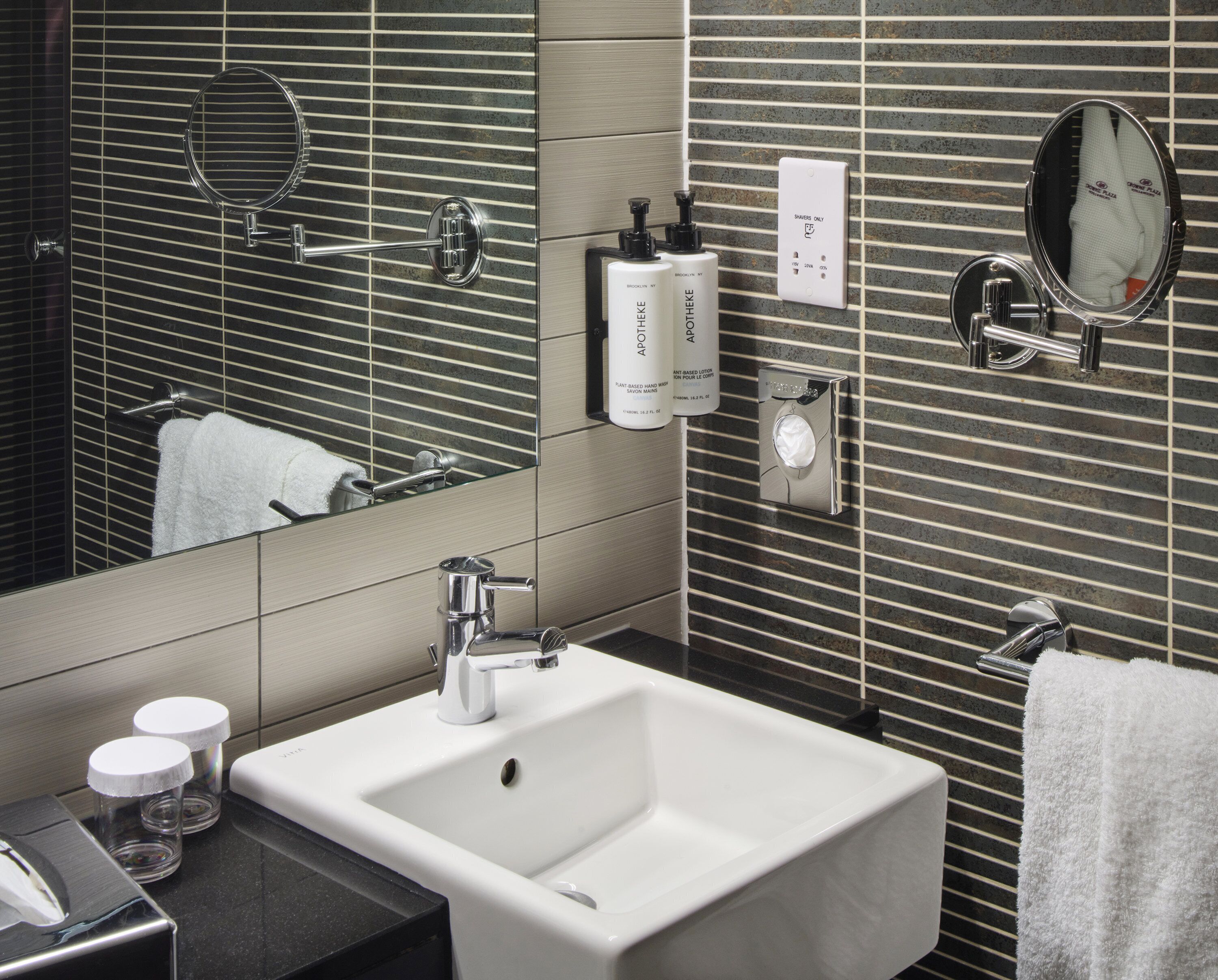Un baño moderno con lavamanos blanco, un espejo y un perchero para toallas.