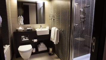 Uma casa de banho moderna com sanita, lavatório e chuveiro.