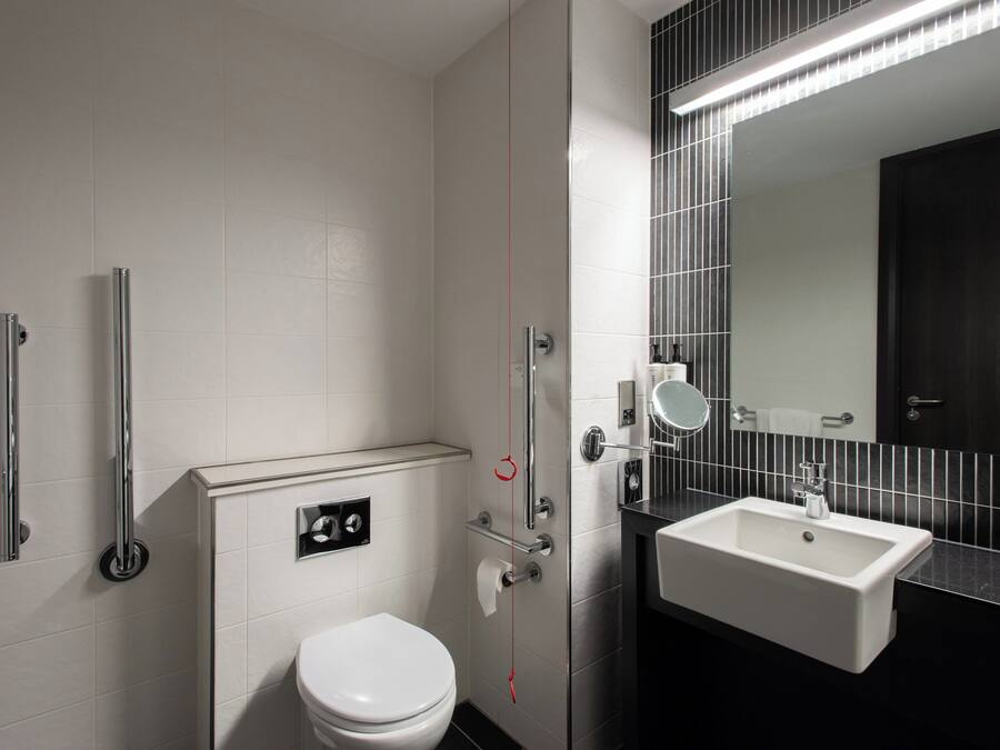 A modern bathroom with a white toilet, a sink, and a mirror.
