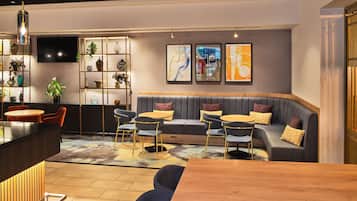 Ein moderner Loungebereich mit einer Couch, runden Tischen und einer Bar.