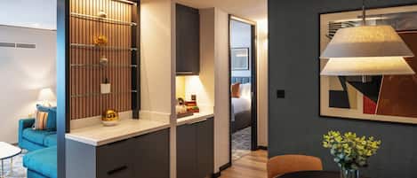 A modern hotel room with a kitchenette, a dining area, and a bedroom.