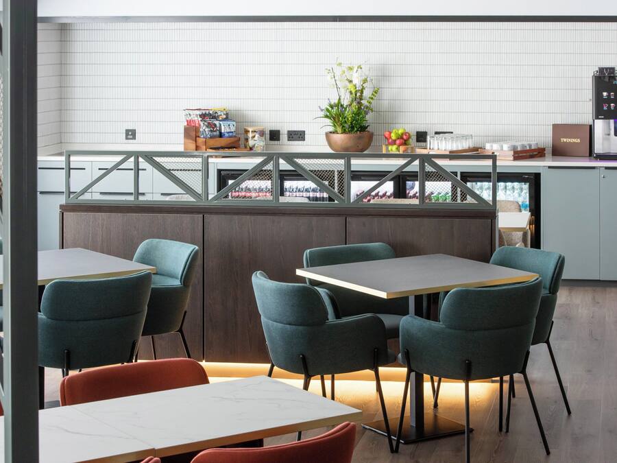 Un restaurante moderno con una zona de bar, asientos y una cocina al fondo.
