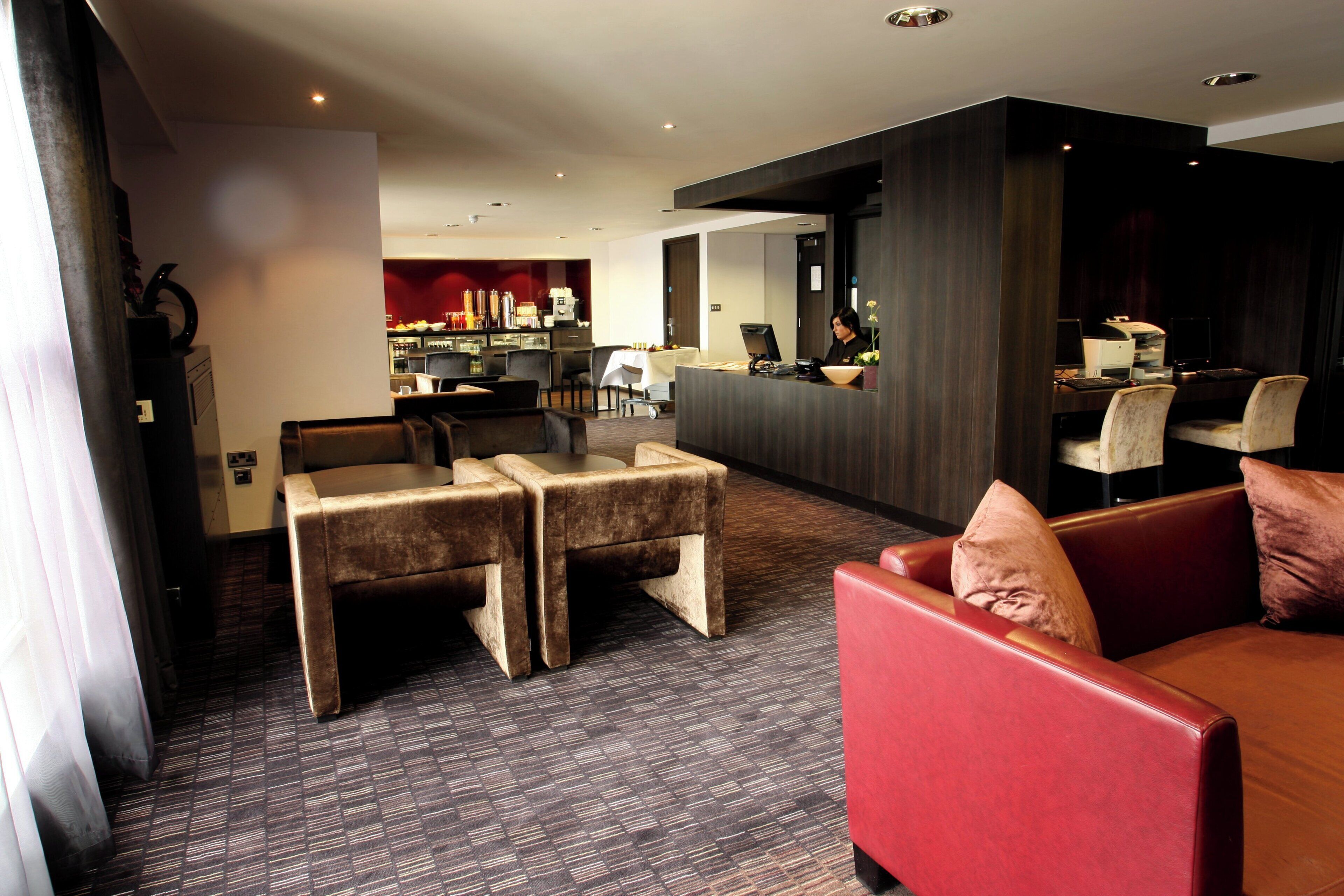 A hotel lobby with seating areas, a reception desk, and a bar.