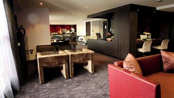 A hotel lobby with seating areas, a reception desk, and a bar.